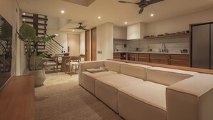 A modern kitchen with a built-in oven, a dining area with a wooden table and chairs, and a beige sectional sofa in the living area. - Luxury penthouse / Heart of Santa Marta (Santa Marta)