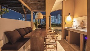 An outdoor seating area with a wooden bench and chairs, a small round table, and a bar with a sink. - Luxury penthouse / Heart of Santa Marta (Santa Marta)