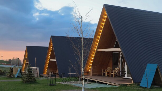Un bâtiment moderne doté de toits triangulaires et d’un petit espace extérieur aménagé avec des chaises et des tables.