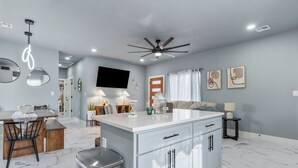 A modern kitchen with a central island, white cabinetry, and a ceiling fan.