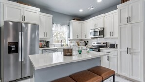 A modern kitchen with white cabinets, stainless steel appliances, and a central island with seating.
