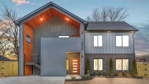 A modern two-story house with a large garage, a covered porch, and a well-maintained front yard.