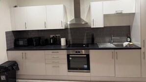A modern kitchen with white cabinets, a black countertop, a stainless steel oven, and a black coffee maker. - Stylish Central Southampton 2-Bed Apartment Perfect for all types of Travelers & (Southampton)