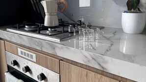 A modern kitchen with a gas stove, a coffee maker, and a potted plant. - Digital Nomad, Expat and Foreign Student Haven! (Pueblo Libre)