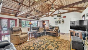 A spacious living room with wooden beams, leather sofas, a large rug, and a television. - Lakefront Lodge w/Dock, Wood Fireplace, Kayaks & Modern Kitchen (Nevada City)