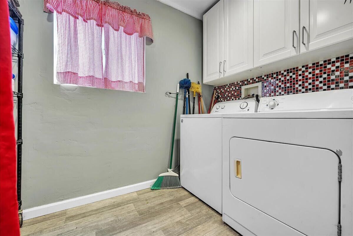 A laundry room with a washing machine, a broom, and cleaning supplies.