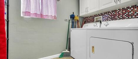 A laundry room with a washing machine, a broom, and cleaning supplies.