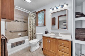 A bathroom with a bathtub, toilet, vanity with a mirror, and a shower curtain. - Lakefront Lodge w/Dock, Wood Fireplace, Kayaks & Modern Kitchen (Nevada City)