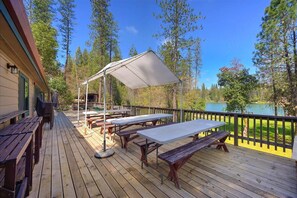 A wooden deck with picnic tables and a canopy, overlooking a lake and surrounded by trees. - Lakefront Lodge w/Dock, Wood Fireplace, Kayaks & Modern Kitchen (Nevada City)