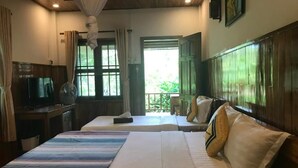 A hotel room with two beds, a television, and a balcony with a view of greenery. - PHU QUOC POMELO GARDEN (Phu Quoc)