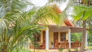 A two-story house with a porch, surrounded by lush greenery and palm trees. - PHU QUOC POMELO GARDEN (Phu Quoc)