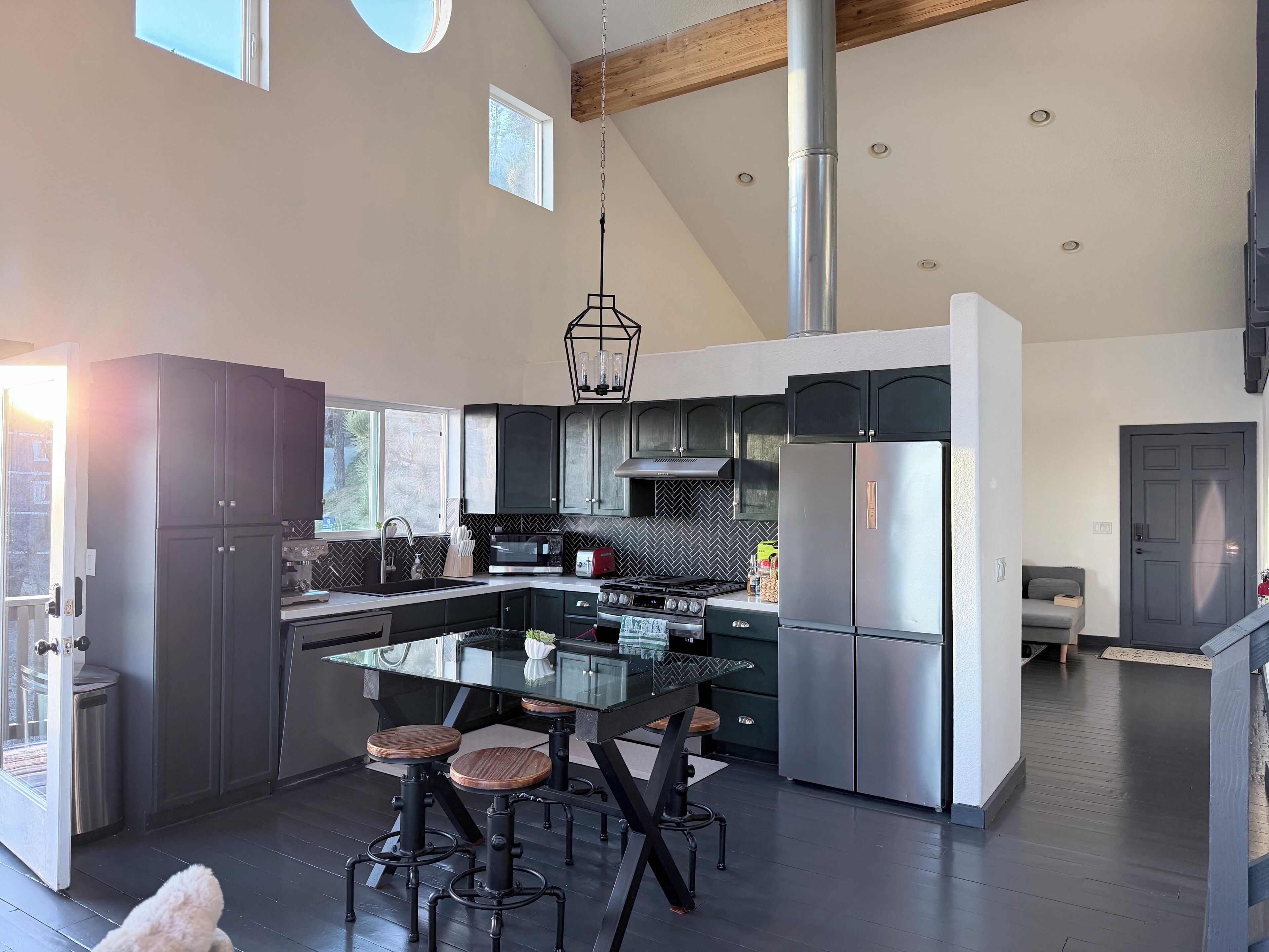 Una cucina moderna con isola centrale, elettrodomestici in acciaio inossidabile e backsplash in piastrelle a spina di pesce.