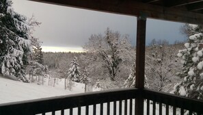 Schneebedeckte Landschaft mit Bäumen und einem Holzbau.