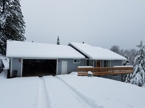 Ein zweistöckiges Haus mit Garage und überdachter Veranda, umgeben von Schnee.