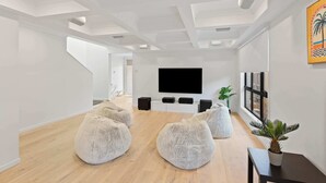 Ein modernes Wohnzimmer mit Flachbildfernseher, Sitzsäcken, einem kleinen Tisch und einer Topfpflanze.