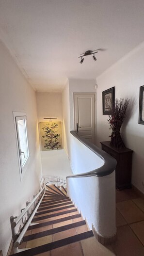 A staircase with a striped carpet, a white wall, a door, and a framed picture. - Typically Provençal, located in the hills above Les Issambres, 6+1 (LES ISSAMBRES)
