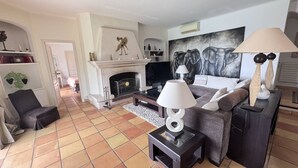 A living room with a fireplace, a sofa, a coffee table, and a TV. - Typically Provençal, located in the hills above Les Issambres, 6+1 (LES ISSAMBRES)