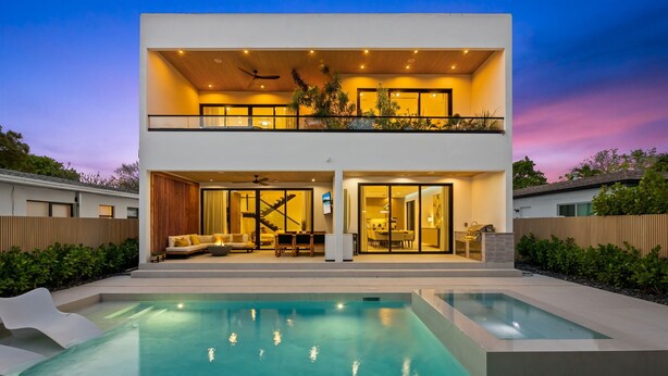 Ein modernes, zweistöckiges Haus mit Schwimmbecken, einem Balkon und einer Treppe, die zum Obergeschoss führt.