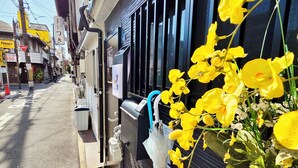 Vista d'un carrer amb un edifici que té una màquina expenedora i un rètol amb caràcters japonesos.