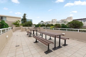 Eine Terrasse im Freien mit mehreren Holzbanken und einem Fliesenboden.