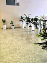 Um corredor com piso de mármore e vários vasos de plantas.