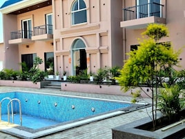 Um edifício moderno com piscina, varandas e plantas em vasos.