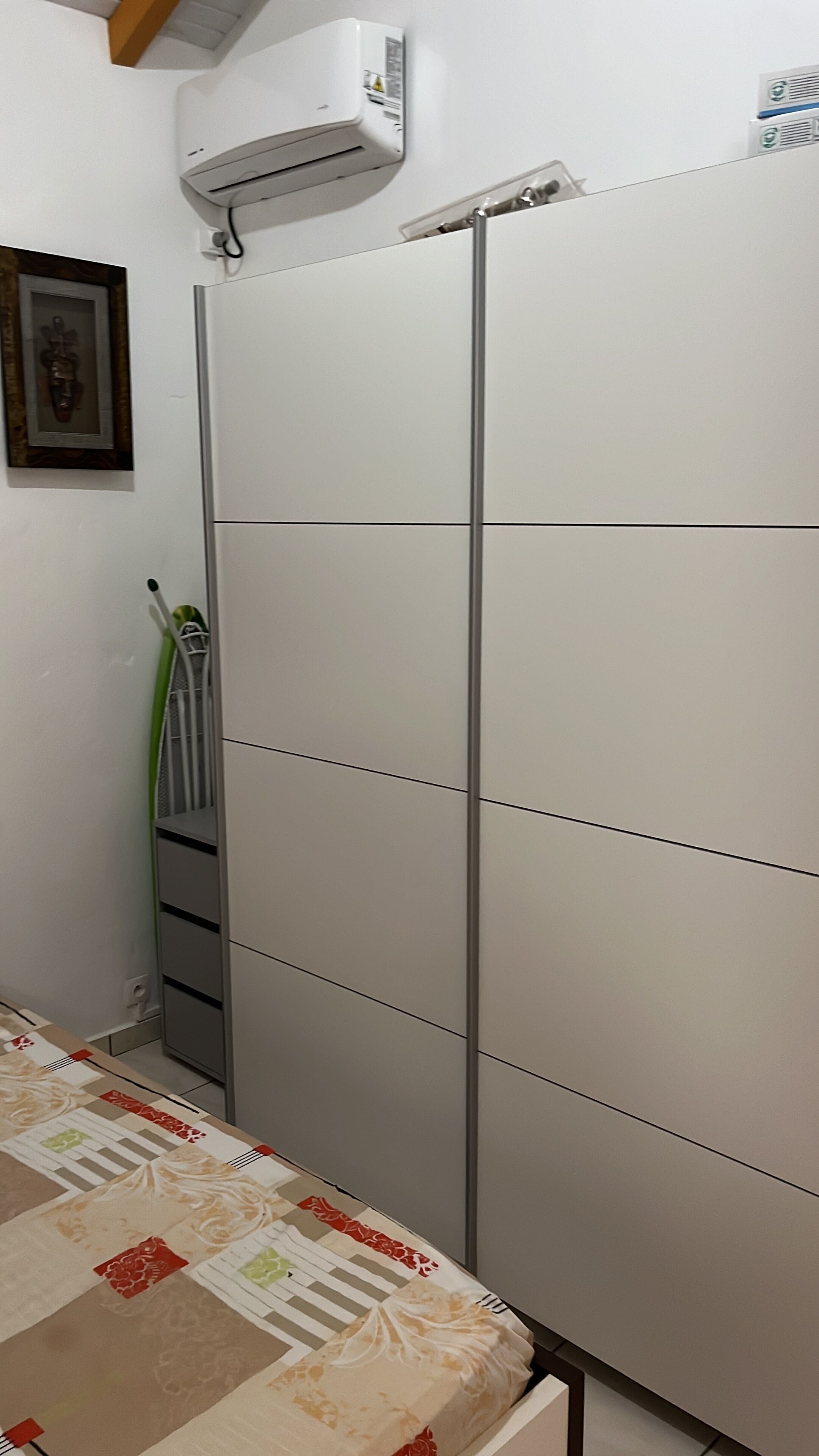 Un dormitorio con cama, armario y aire acondicionado.
