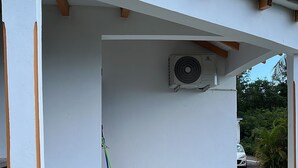 Een overdekt buitengebied met een tafel, stoelen, een wasmachine en een bezem.