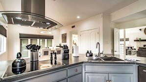 Una cocina moderna con extractor de acero inoxidable, un lavamanos integrado y encimera de granito.