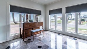 Una habitación con amplios ventanales, un banco y un piano.