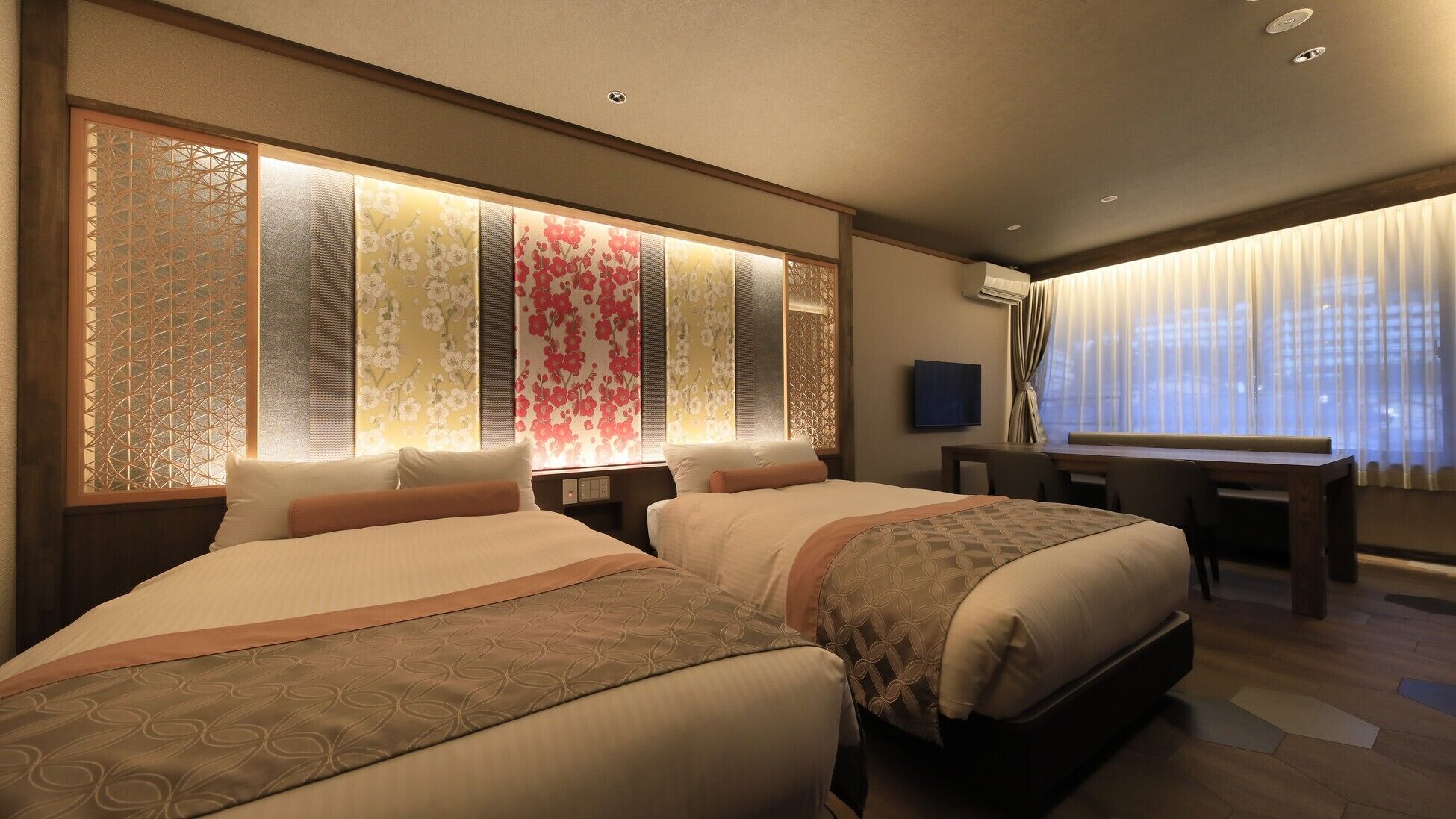 A hotel room with two beds, a desk, and a TV.