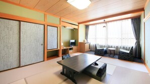 Una habitación tradicional japonesa con suelo de tatami, una mesa baja y puertas correderas.
