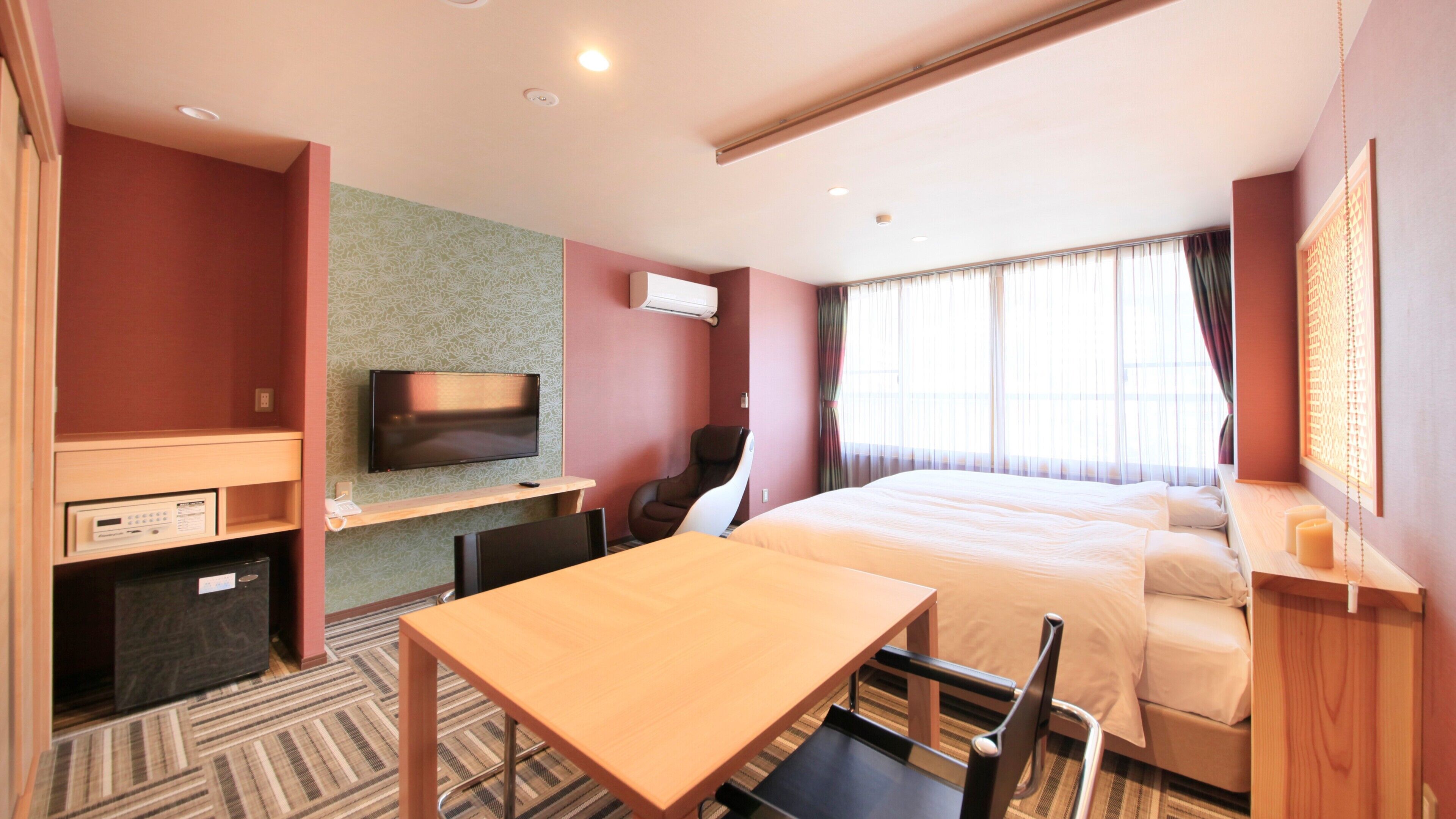 A hotel room with a bed, a desk, a chair, a TV, and a massage chair.