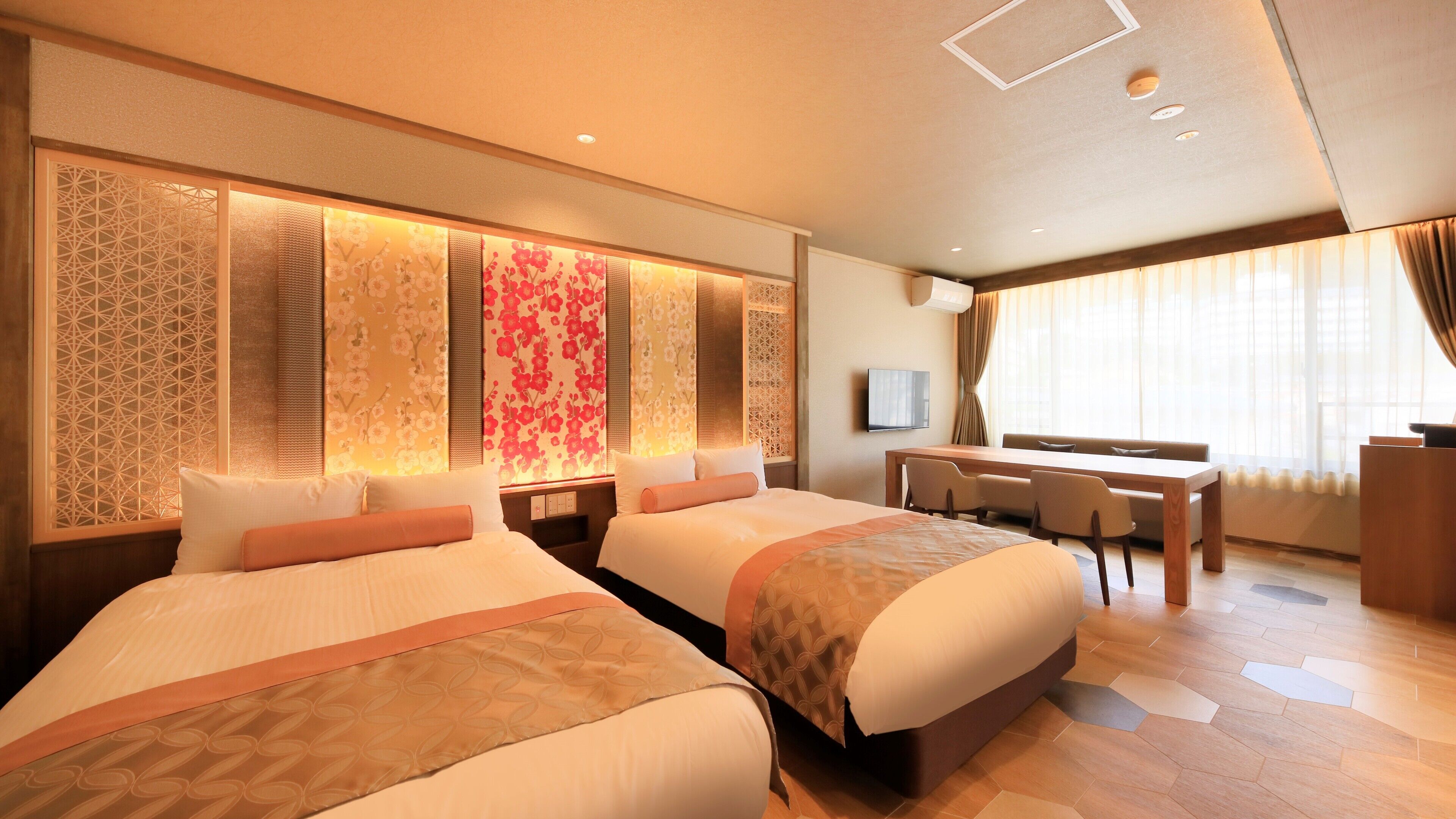A hotel room with two beds, a desk, a chair, a TV, and a window with curtains.