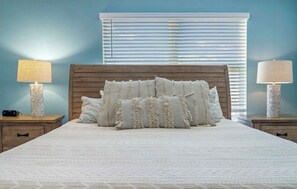 Un dormitorio con una cama grande, dos mesitas de noche y una ventana con persianas.