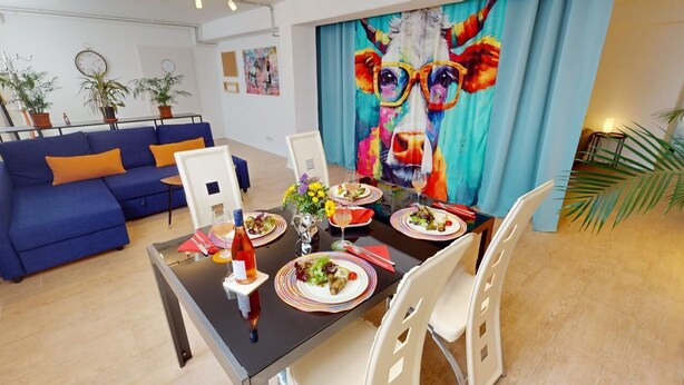 A dining area with a table set for four, surrounded by blue sofas and white chairs. - Apartment Konstanz - Urban living for fitters, business travelers and holidaymakers (Konstant)