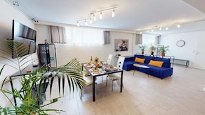 A modern living room with a sofa, dining table, and a TV. - Apartment Konstanz - Urban living for fitters, business travelers and holidaymakers (Konstant)