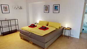 A modern bedroom with a double bed, two bedside tables, and a small desk with a chair. - Apartment Konstanz - Urban living for fitters, business travelers and holidaymakers (Konstant)