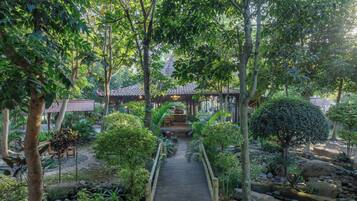A pathway leading to a traditional-style building surrounded by lush greenery and trees.