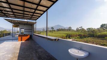 A covered outdoor area with a sink and a view of a green landscape.
