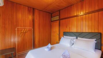 Una habitación de hotel con paredes de paneles de madera, una cama con ropa blanca y un banco.