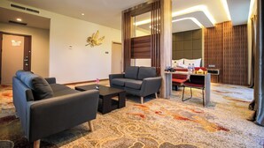 A modern hotel room with a sofa, armchair, and a small desk with a chair. - Gayo Petro Hotel (Takengon)