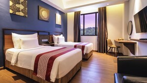 A hotel room with two beds, a desk, a chair, and a TV. - Gayo Petro Hotel (Takengon)