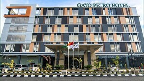 A modern hotel building with a prominent entrance and a flag. - Gayo Petro Hotel (Takengon)