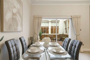 A dining area with a glass table, leather chairs, and a view of the outside. - Hertford Flat 1 (London)