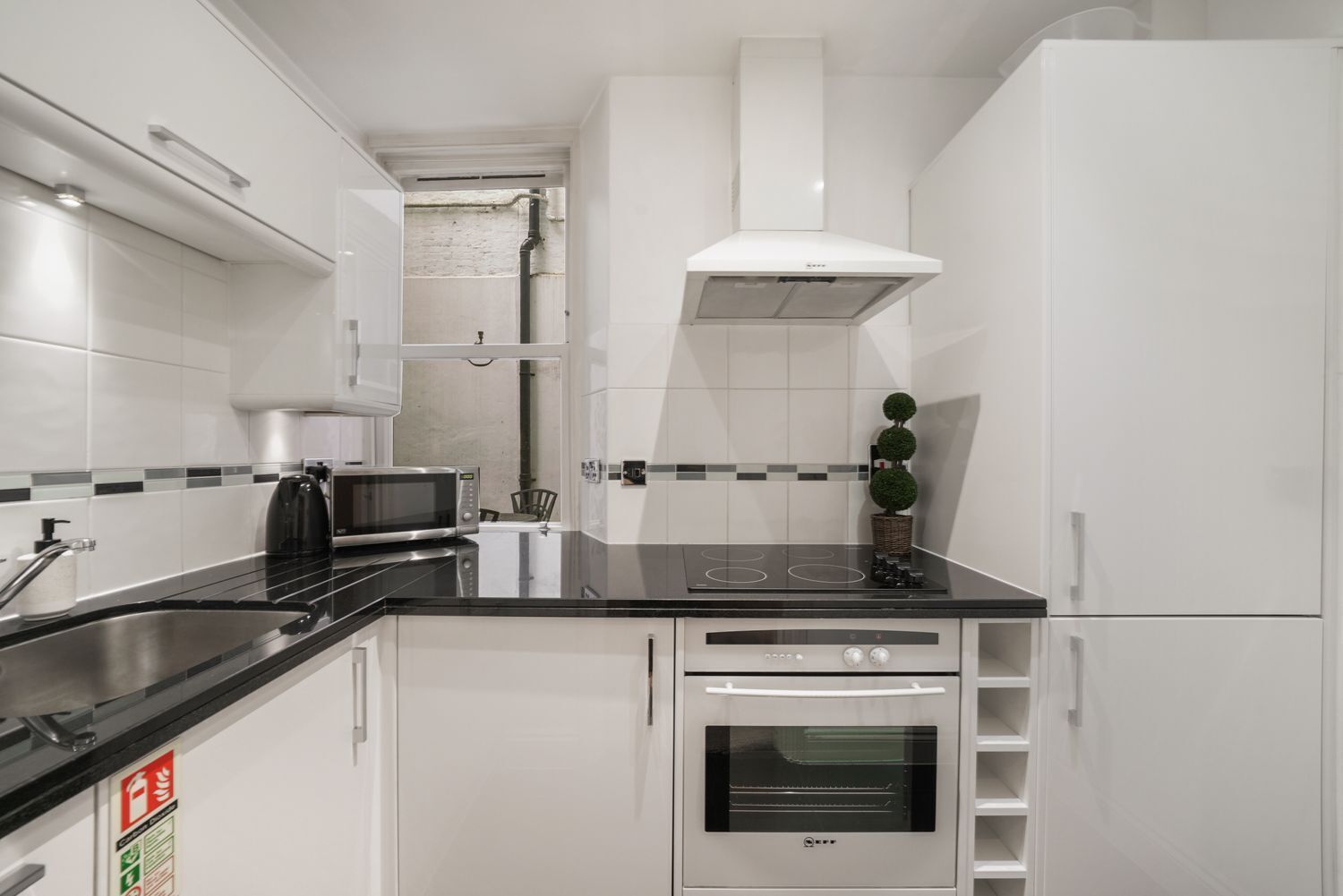 A modern kitchen with a black countertop, stainless steel appliances, and white cabinetry.