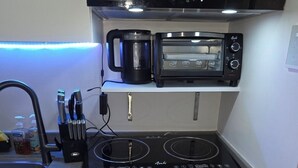 A compact kitchen with a built-in microwave, toaster, and induction cooktop. - Cozy 1-bedroom riverfront condo in serene area with AC (Mandaluyong City)