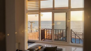 Una habitación con un ventanal grande que da a una terraza de madera y al mar.