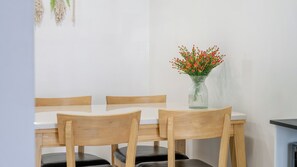 A dining area with a table and four wooden chairs, a vase with red flowers, and a wall with a macrame decoration. - Gyeongju Sea View Pool Villa (Gyeongju)