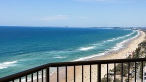 Udsigt over kysten fra en balkon med udsigt over en strand, klart himmel.